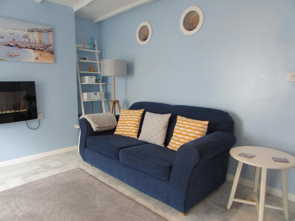 ein blaues Wohnzimmer mit einem blauen Sofa und einem Tisch in der Unterkunft The Cuddy - Apartment with garden in Brixham