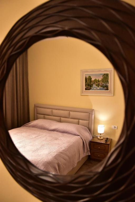- une chambre avec un lit et un miroir rond dans l'établissement Vila Visi Hotel, à Korçë
