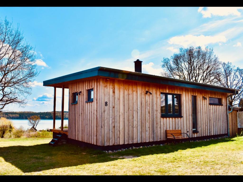 a small wooden cabin in a field with a lake at Ferienhaus M&M in Schwarz