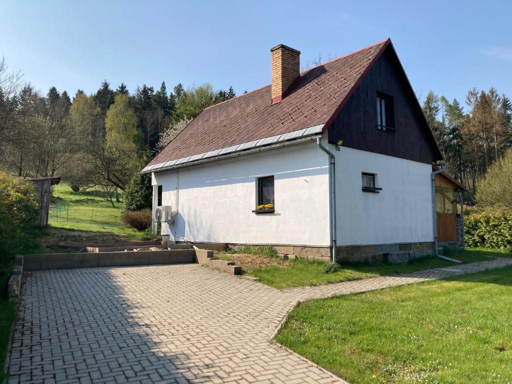 uma casa branca com um telhado castanho e uma entrada de tijolos em Chata Rožany em Šluknov
