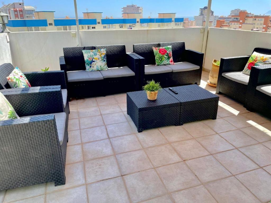 a patio with couches and a table on a roof at ÁTICO COPACABANA in Playa de Gandia