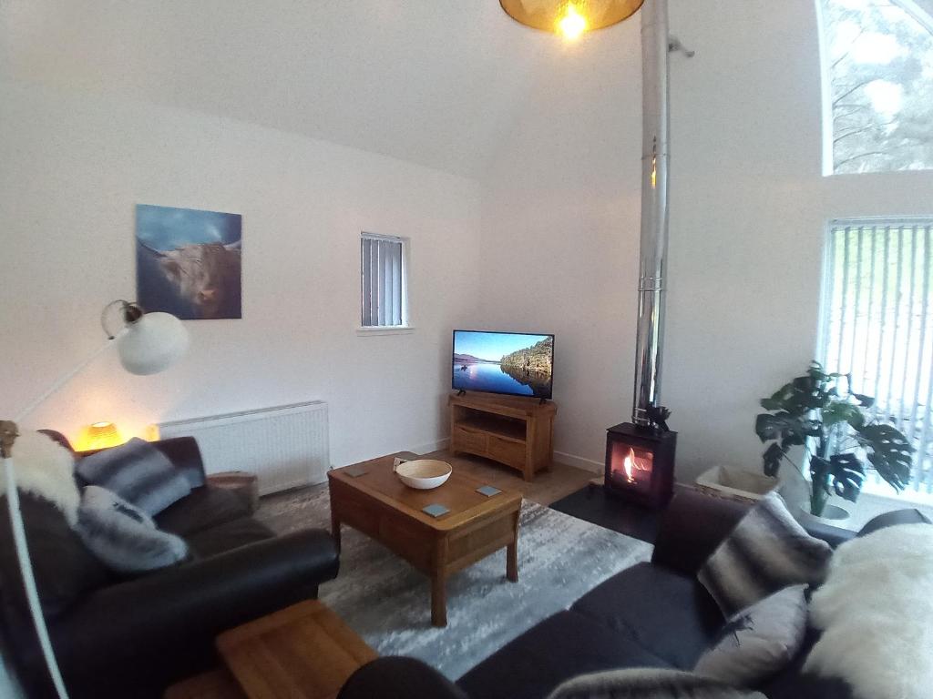 a living room with a couch and a tv at Sawmill Cottage in Grantown on Spey