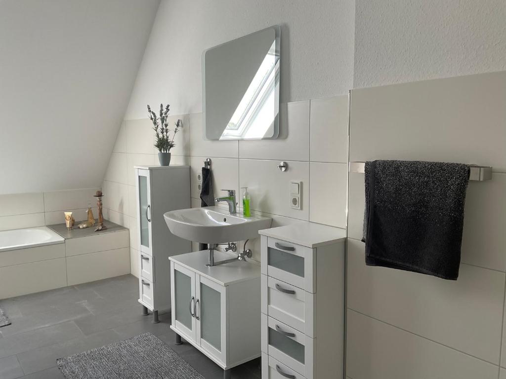 ein weißes Badezimmer mit einem Waschbecken und einem Spiegel in der Unterkunft Ferienhaus Smidt in Emden