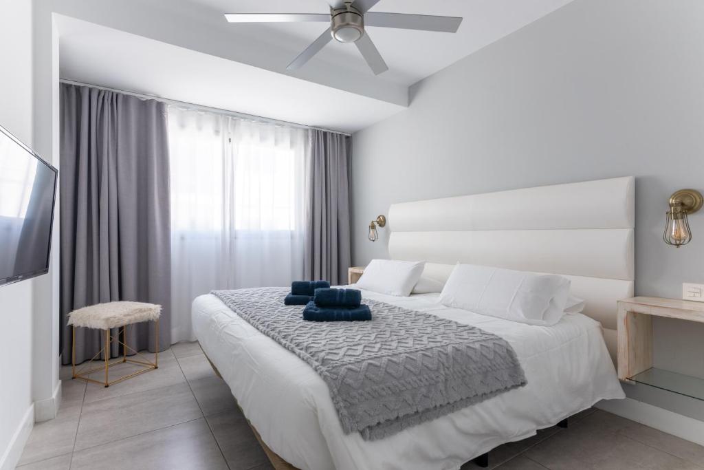 een witte slaapkamer met een bed en een plafondventilator bij Abubilla HolidayFV in Corralejo