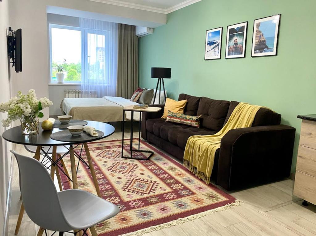 uma sala de estar com um sofá e uma mesa em Апартаменты-студия Көктем с видом на город em Almaty