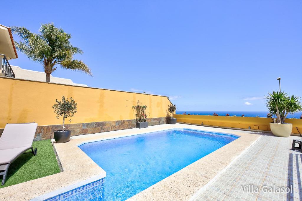 a swimming pool on the side of a house with the ocean at Villa Galasol with heated pool in Radazul