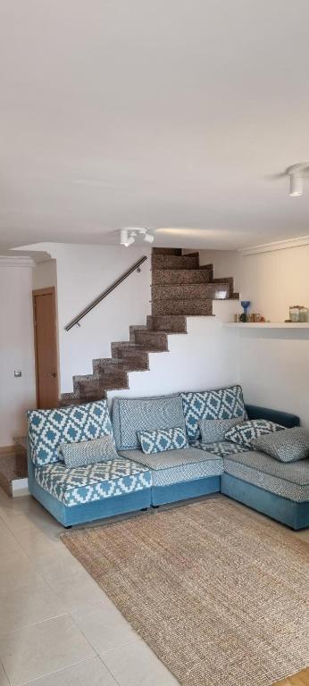 a living room with a blue couch and stairs at duplex appartement met zwembad, L'ampolla, in L'Ampolla