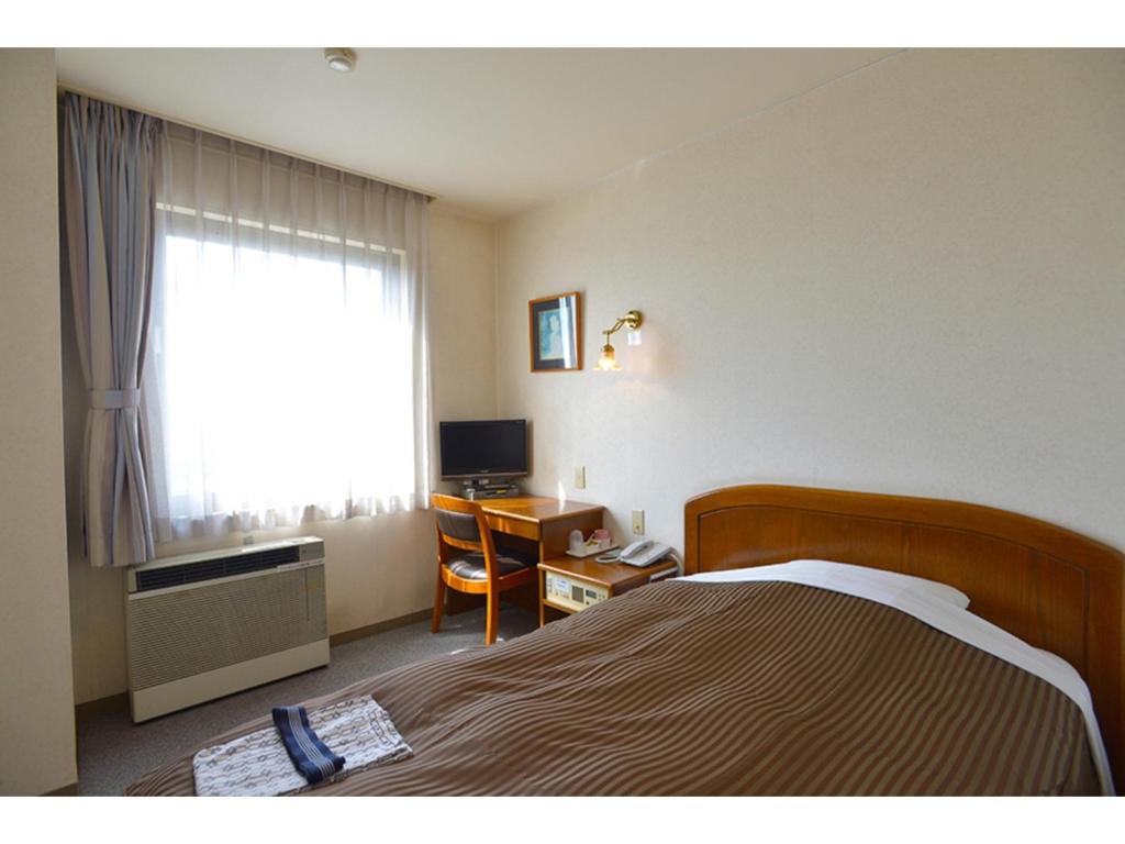 a hotel room with a bed and a desk and a window at Famy Inn Makuhari - Vacation STAY 16033v in Chiba