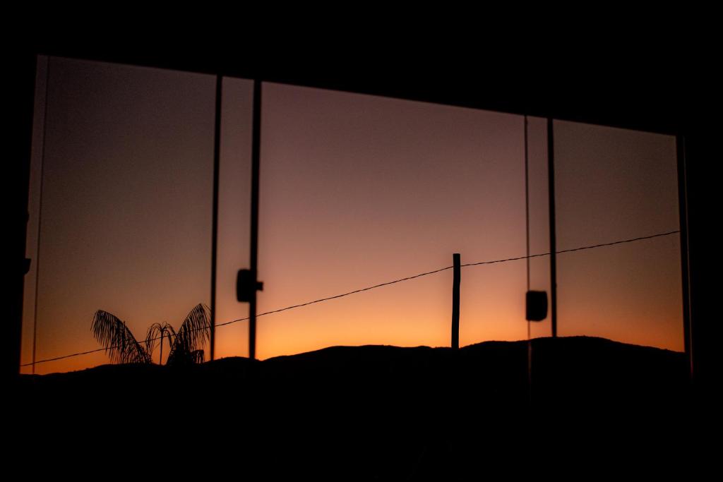una puesta de sol vista a través de una ventana de cristal en Casa Canastra Bio en São Roque de Minas