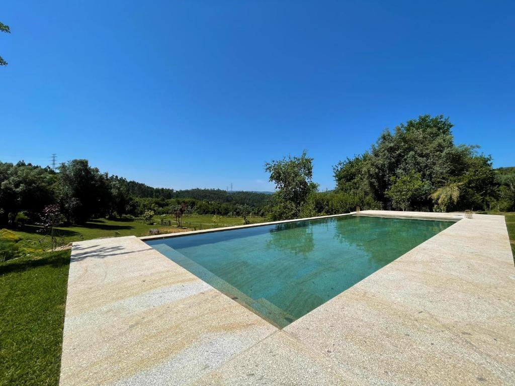 a swimming pool in the middle of a field with trees at Casa de Vilar de Rei, férias em família com piscina in Ponte de Lima