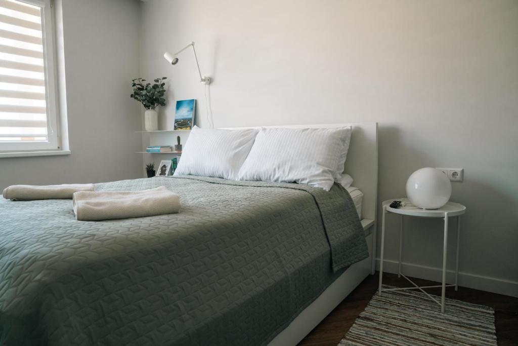 ein Schlafzimmer mit einem Bett mit einer grünen Decke in der Unterkunft Grey Green Studio Apartment in Birštonas