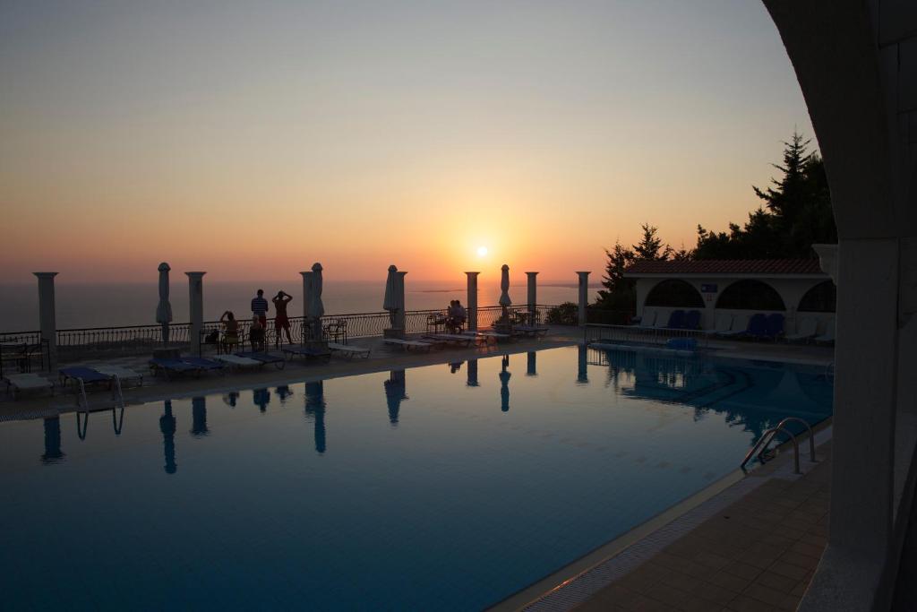 een zwembad met een zonsondergang op de achtergrond bij Mouikis Sun Village in Lakíthra