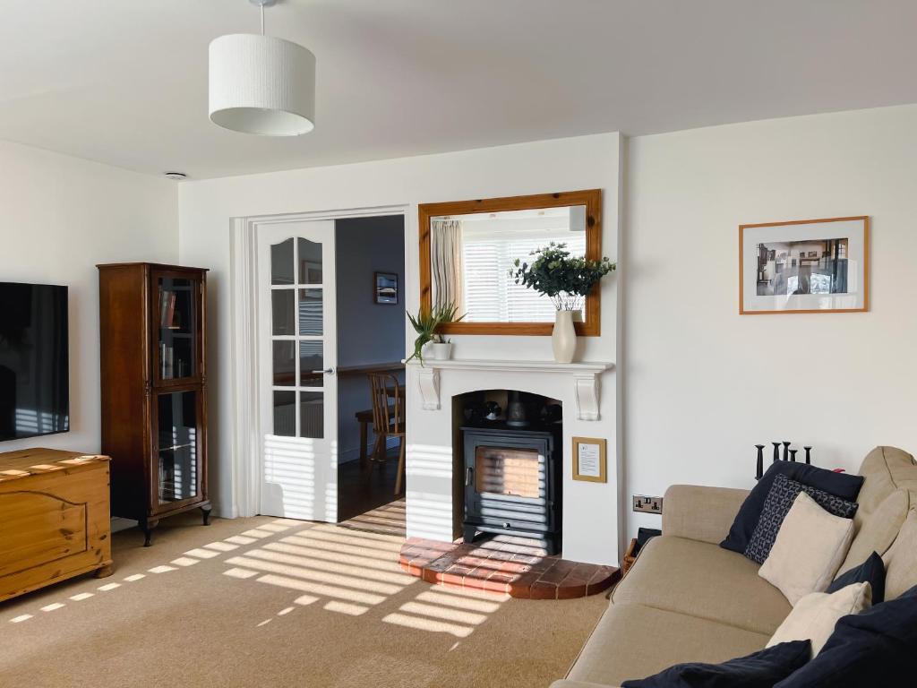 a living room with a couch and a fireplace at Bright & Cosy - Jacuzzi - Log Burner - King Beds in Tangmere