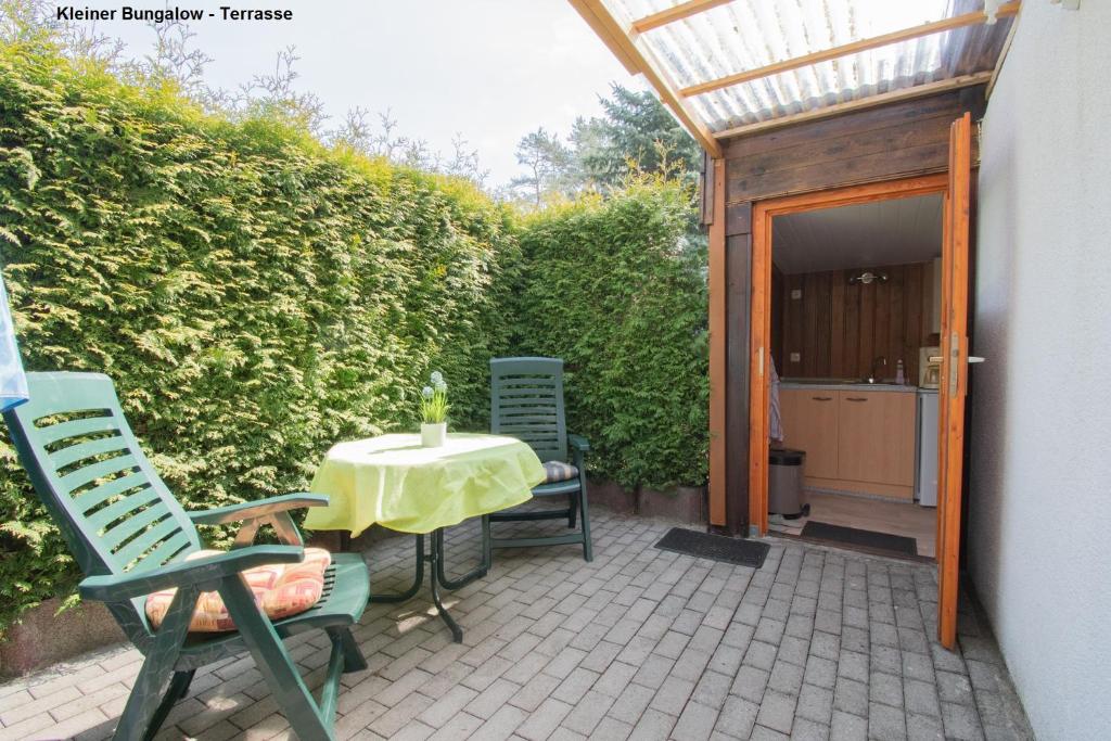 a patio with a table and chairs next to a building at Kleiner Bungalow - Zum Strand 50m in Ueckeritz