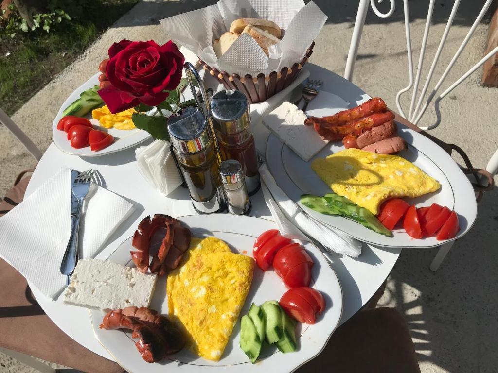 two plates of breakfast food on a table with roses at InTown Guesthouse Shkoder in Shkodër