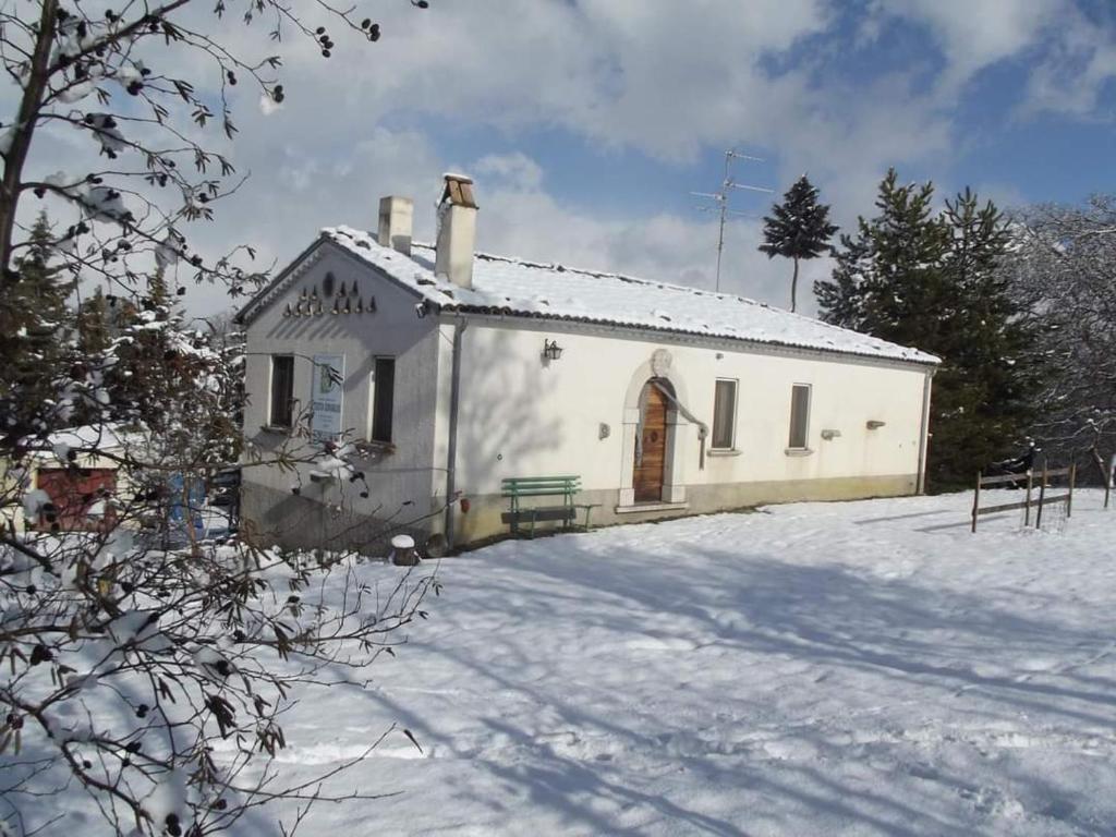 a small white building in the snow with trees at Agriturismo Masseria Testa Ciruglio in Ielsi