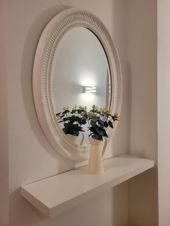 un espejo en un estante con un jarrón con flores en Piso Stylety Alcazar, en Talavera de la Reina