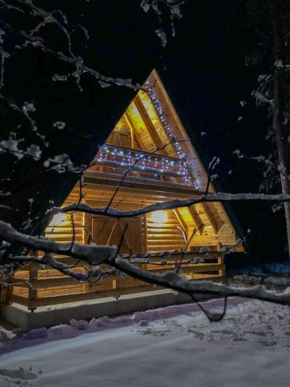 a log cabin with lights on it in the snow at The Pine Forest Cottage in Žabljak