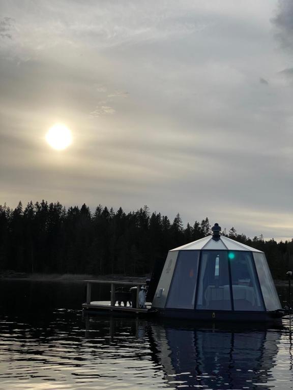 a small boat on a lake with the sun in the sky at Yggdrasil Igloo Värmland in Töcksfors