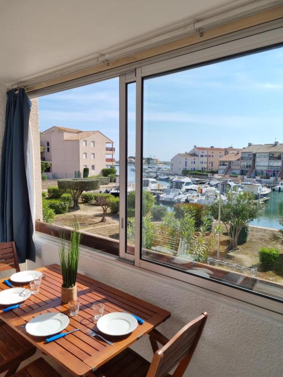 una sala da pranzo con tavolo e una grande finestra di Appartement avec vue exceptionnelle sur la marina a Saint-Cyprien