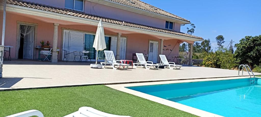 a villa with a swimming pool and chairs and a house at Casa do soito in Mangualde