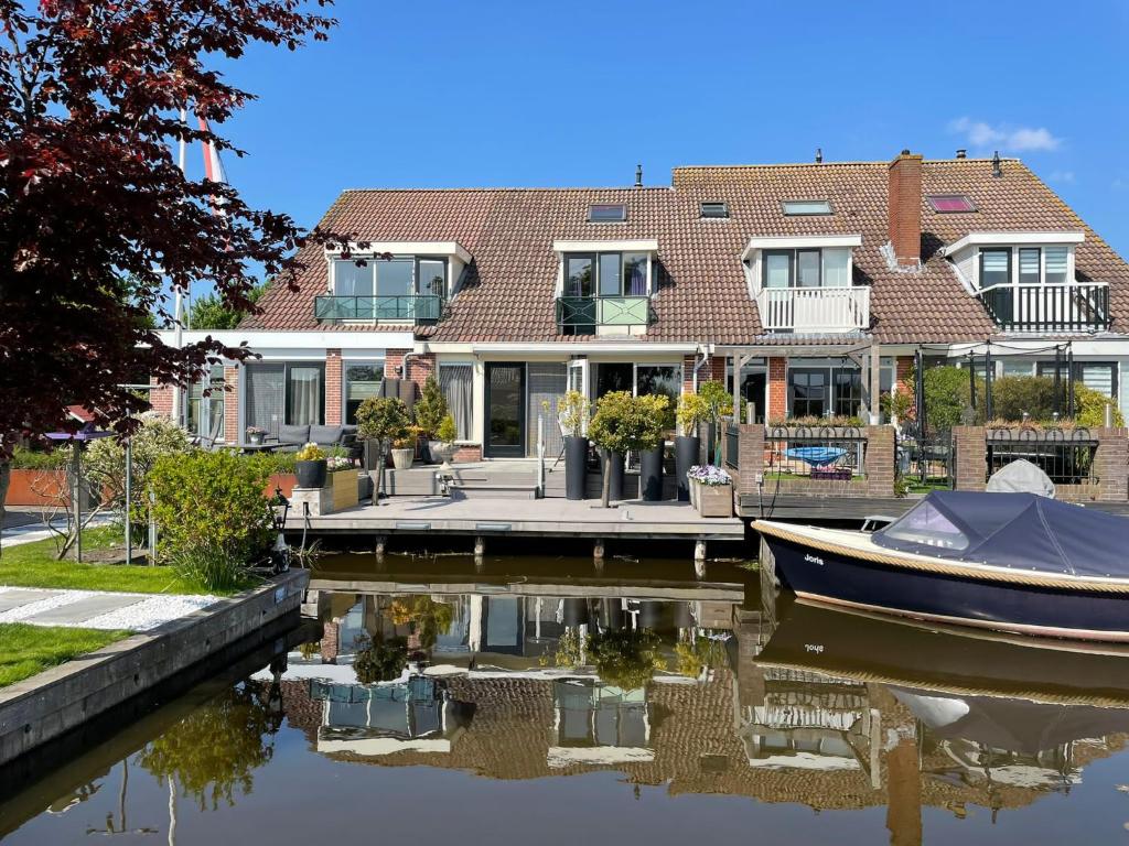 a house with a boat in the water at Guesthouse BedNboot met terras aan het water in Rijpwetering