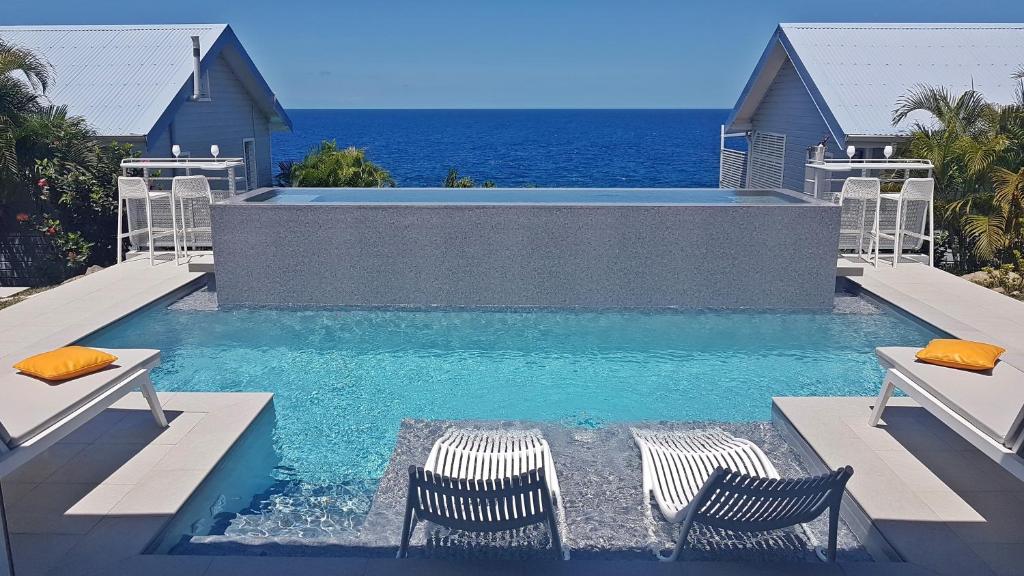 een zwembad met twee stoelen en de oceaan bij Blue Haven Villas Guadeloupe Villa Blue Star in Bouillante