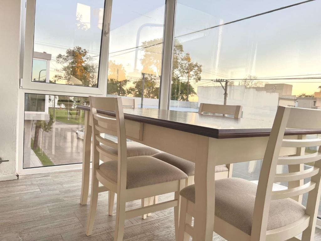 a dining room table with chairs and a large window at Gran departamento a metros de la laguna para parejas in Chascomús