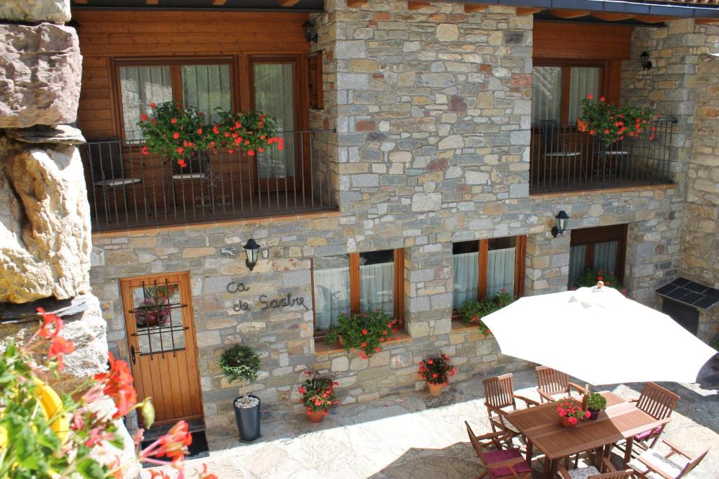 um edifício de pedra com uma mesa e um guarda-chuva em Turismo Rural Casa Sastre em Forcat