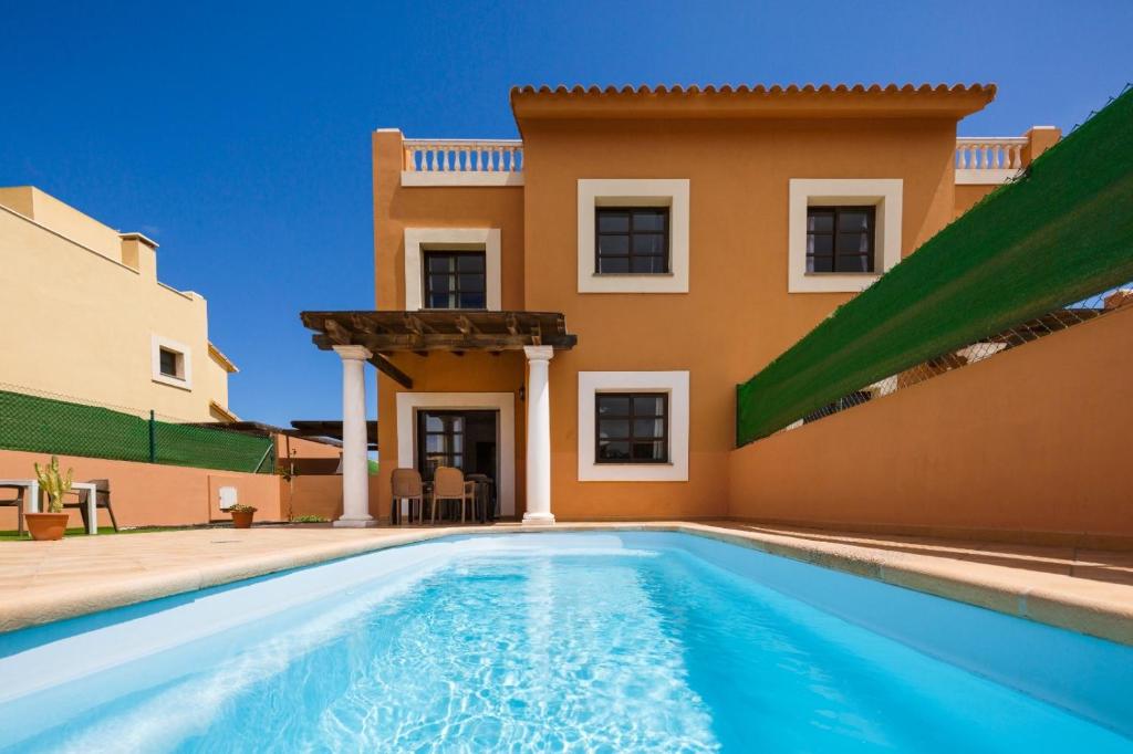 eine Villa mit einem Pool vor einem Haus in der Unterkunft FTV Holidays Homes in Corralejo