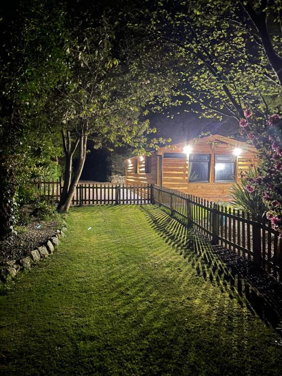 a cabin in a yard at night with a fence at Snowdonia cabin in Caernarfon