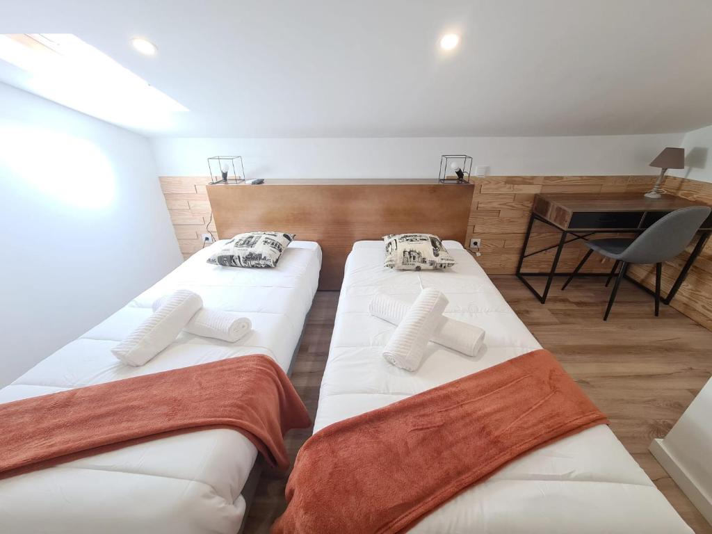two beds in a room with a table and a chair at COIMBRA CITY CHARM in Coimbra