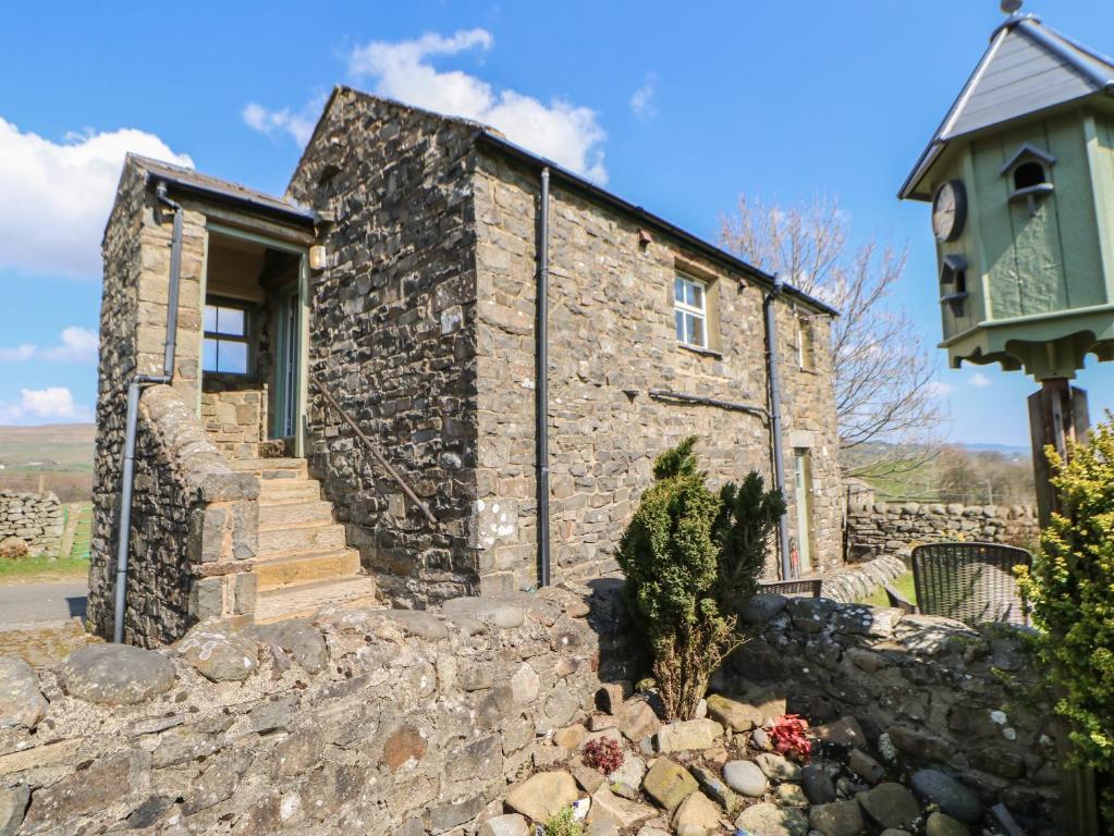 an old stone house with a stone wall and stairs at Meadows Edge in Holwick