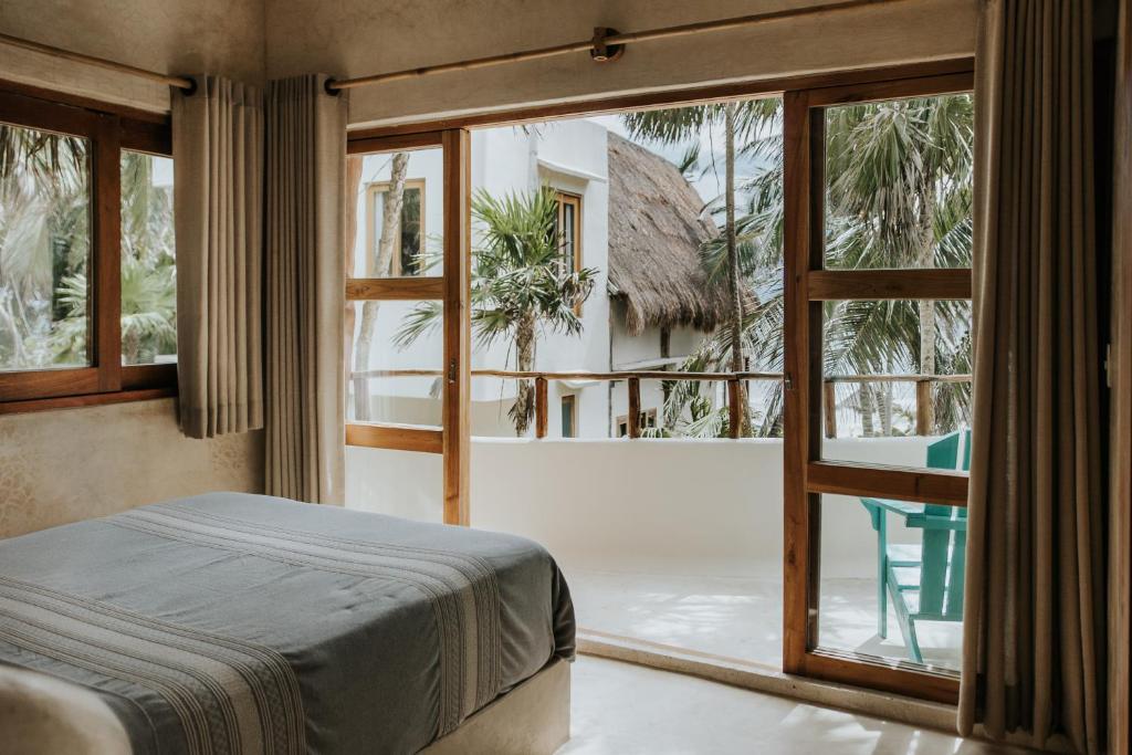 a bedroom with a bed and a large window at Mahayana Tulum Beach Homes in Tulum