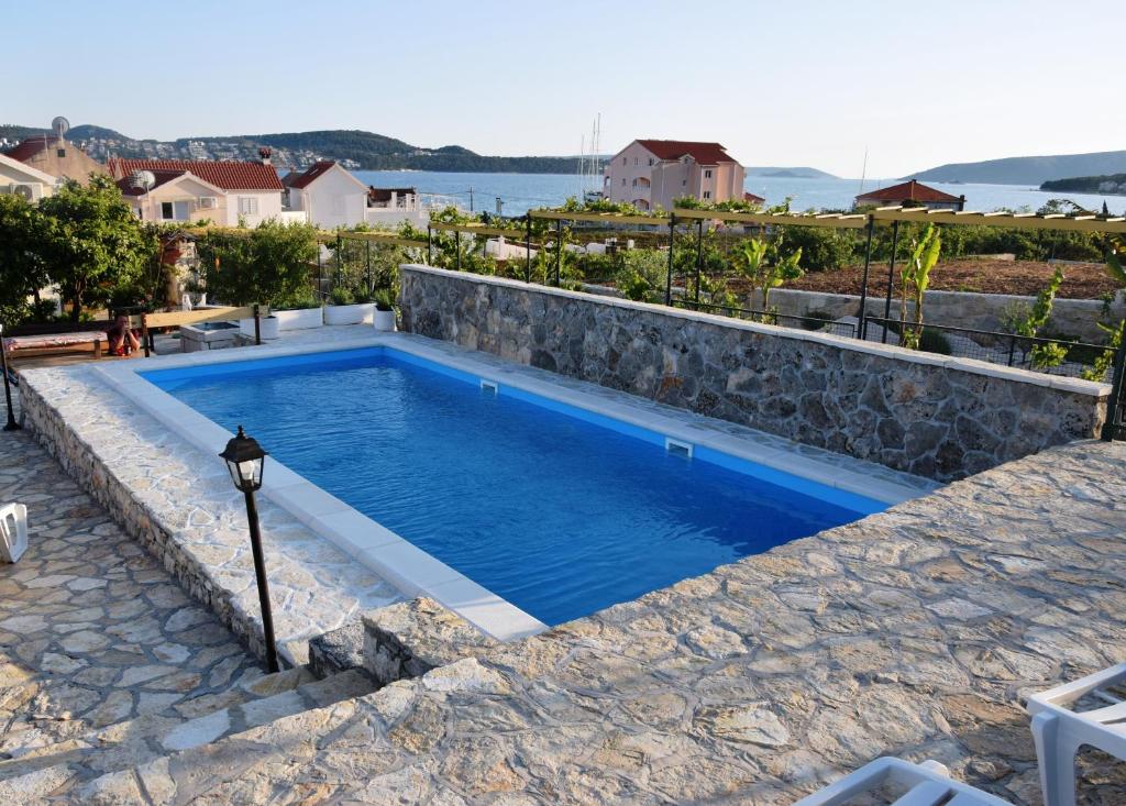 a swimming pool with blue water and a stone wall at Two-Bedroom House with Shared Pool in heart of Seget in Trogir