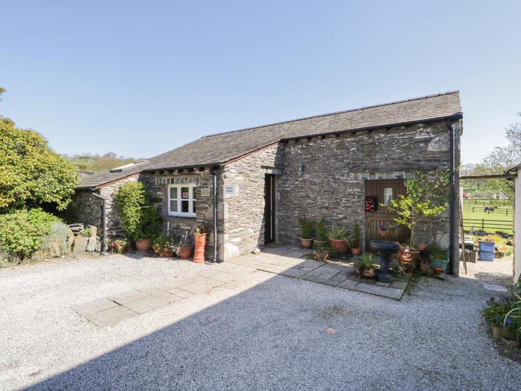 a stone barn with a driveway in front of it at Topiary Cottage in Staveley