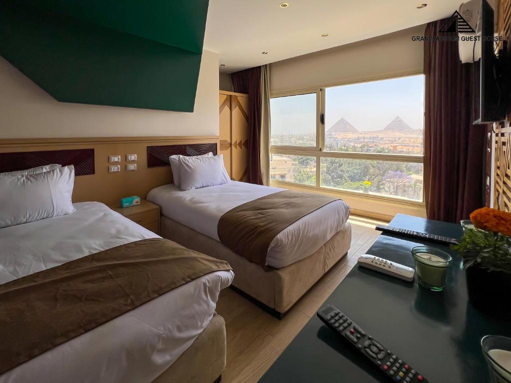 a hotel room with two beds and a desk and a window at Grand Museum Guest House, pyramids view in Cairo