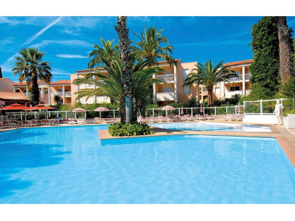 une grande piscine avec des palmiers et des bâtiments dans l'établissement T2 A/C côte d'Azur, piscine, plage á 350m, WIFI, à Vallauris