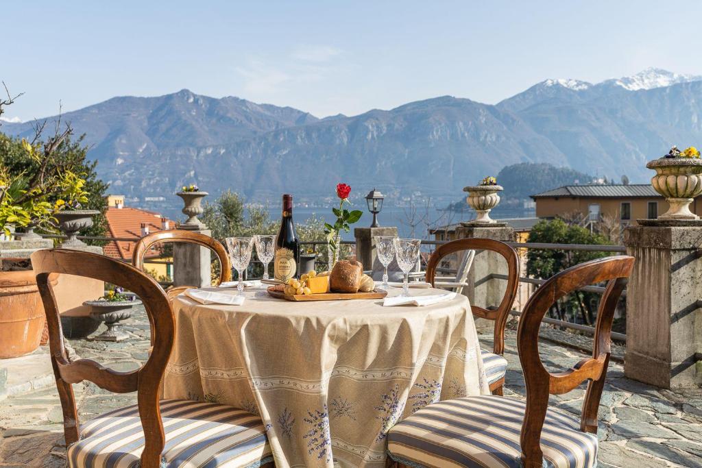 - une table avec une bouteille de vin sur un balcon avec des montagnes dans l'établissement Villa Caterina, à Griante Cadenabbia