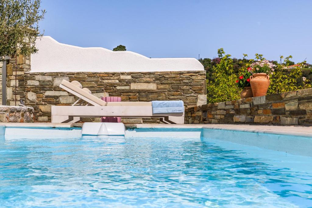 una piscina con un banco en el agua en Villa Mariel Skopelos, en Skopelos Town