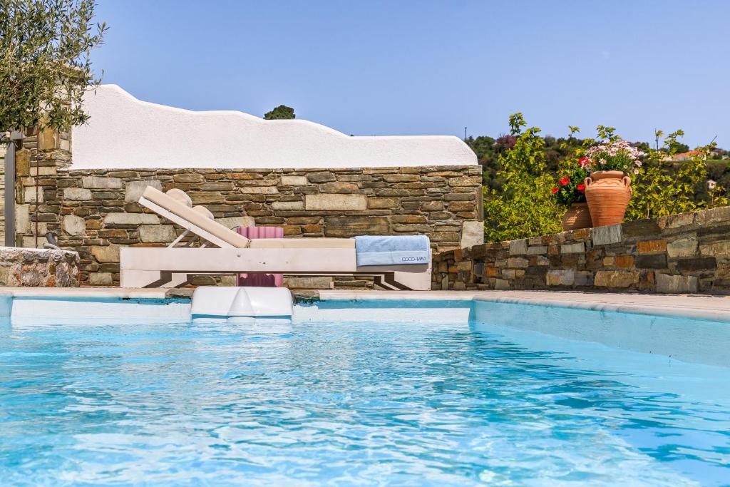 a swimming pool with a bench in the water at Villa Mariel Skopelos in Skopelos Town