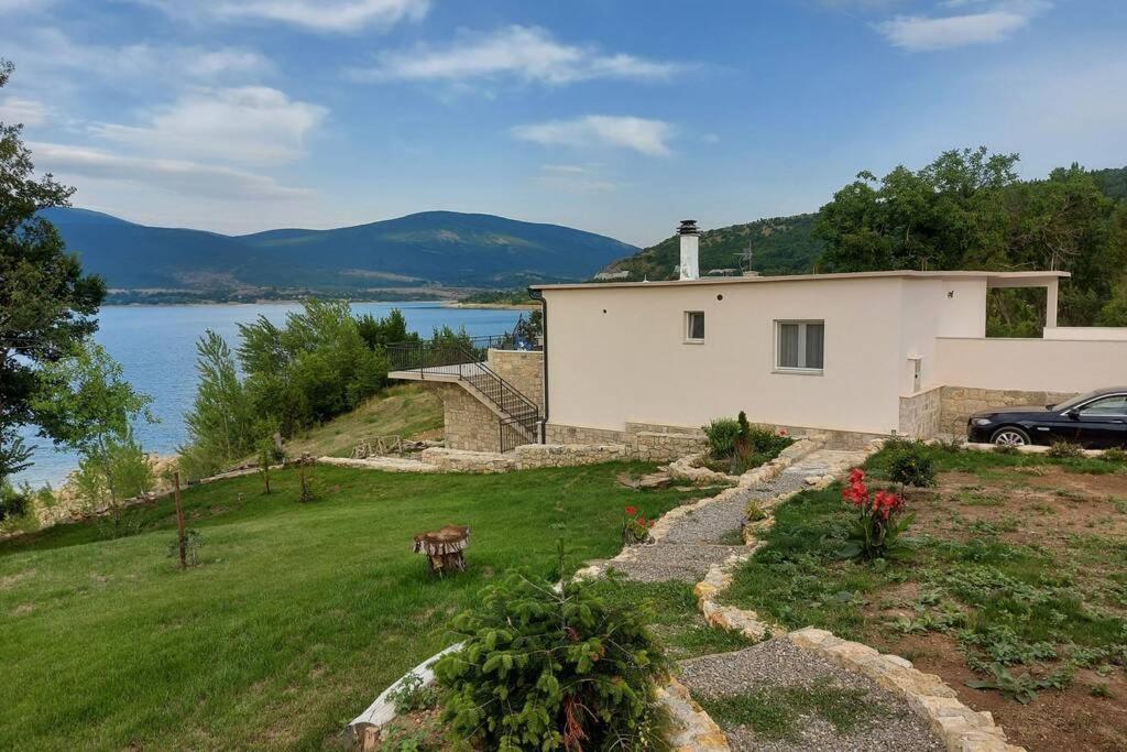ein Haus auf einem Hügel neben einem Wasserkörper in der Unterkunft Vrlika, Peruća Lake Holiday House in Vrlika
