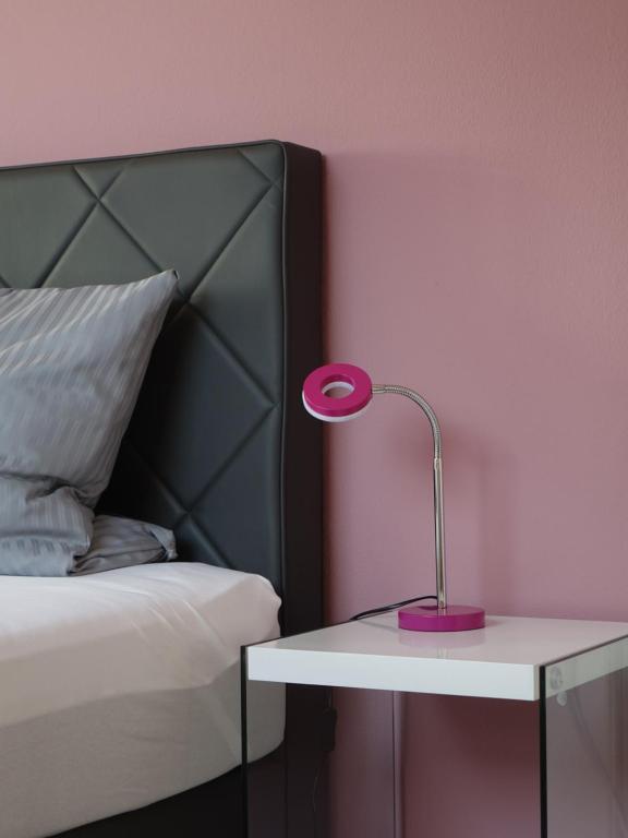 una lámpara rosa sobre una mesa junto a una cama en Das SinGold Hotel mit Highspeed WLAN und digitalem Schlüssel, en Schwabmünchen