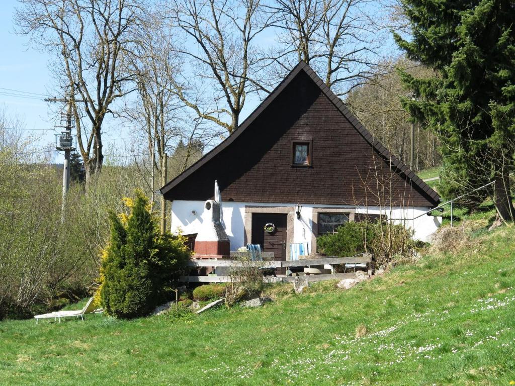 una pequeña casa con un techo negro en una colina en Detached and cozy holiday home with terrace in the Black Forest, en Brigach