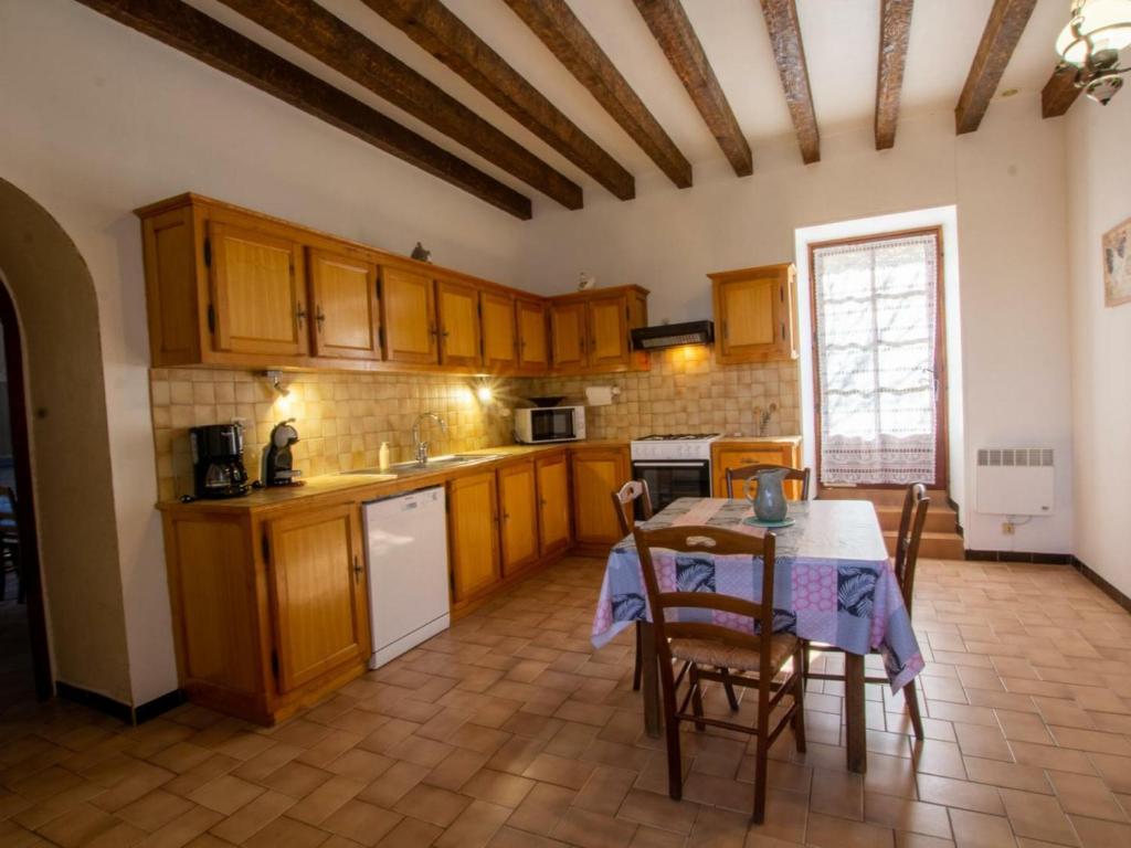 a kitchen with wooden cabinets and a table with chairs at Gîte Domme, 5 pièces, 8 personnes - FR-1-616-23 in Domme