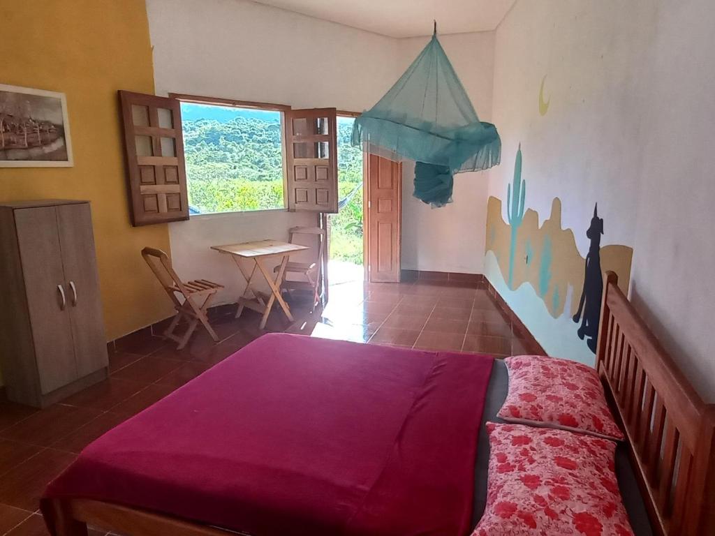 a bedroom with a bed and a table and a window at Pousada Serra Aquarela in Ibicoara