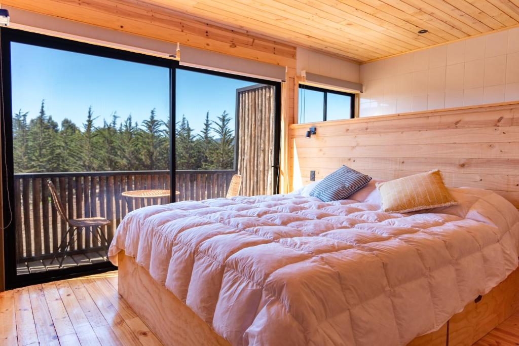 a large bed in a room with a balcony at 360 Lodge Pichilemu in Pichilemu