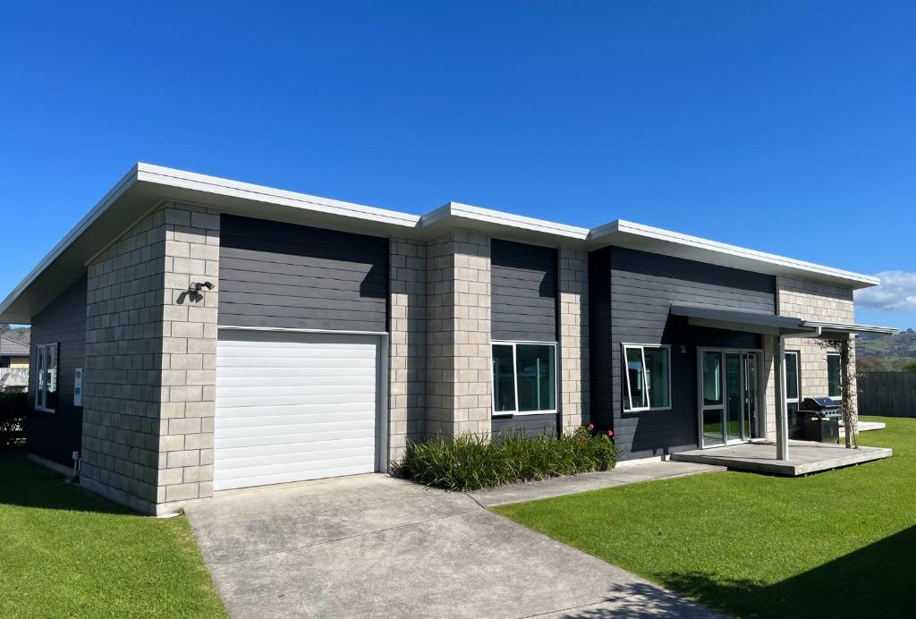 a house with a white garage at Surfers Retreat - Waihi Holiday Home in Waihi Beach