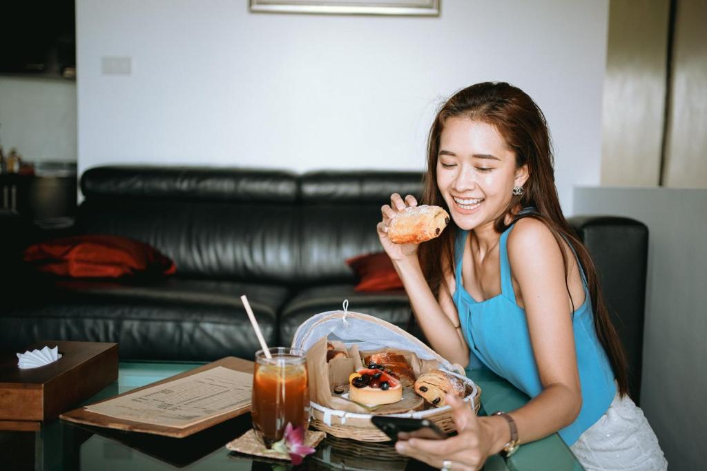 a woman eating a donut in front of a table at The Front Hotel and Apartments in Patong Beach