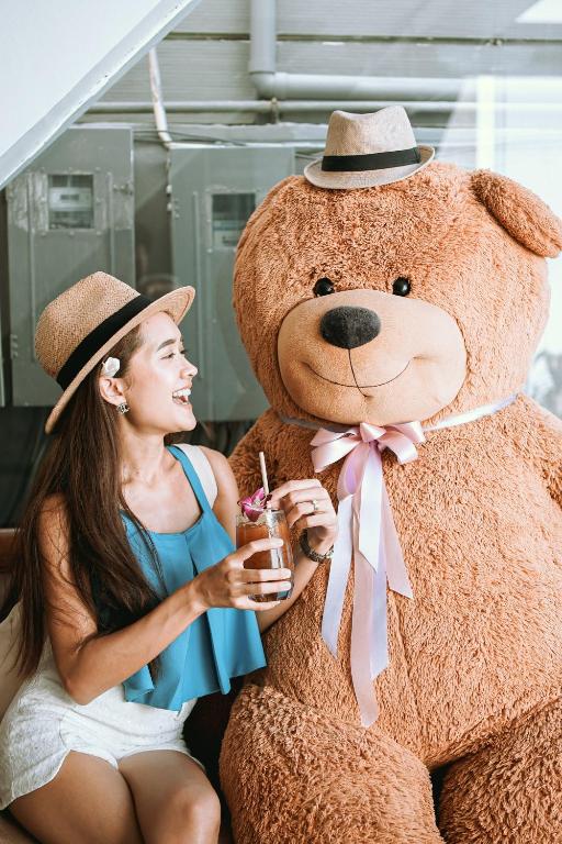 a woman is sitting next to a giant teddy bear at The Front Hotel and Apartments in Patong Beach